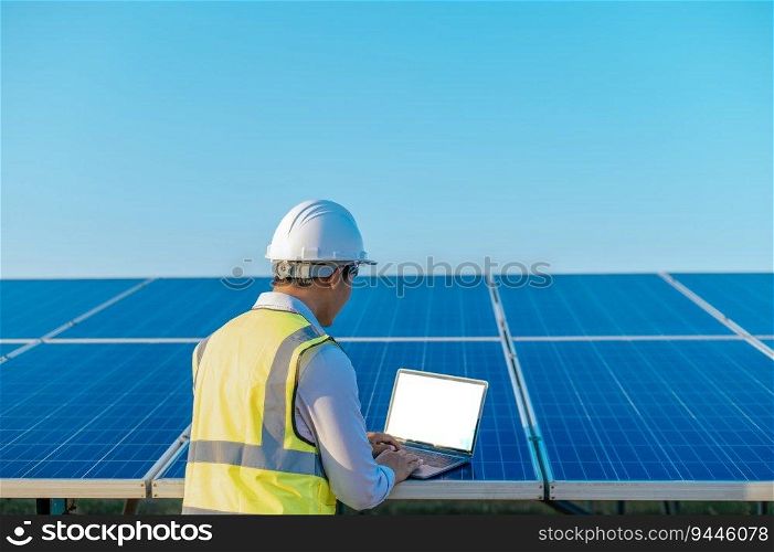 Young Asian Inspector Engineer man use laptop computer working at solar farm, Technician, supervisor male in white helmet Checking operation of sun and photovoltaic solar panel in station, copy space