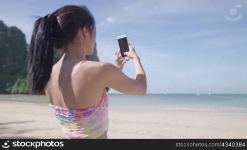 Young asian lady taking snapshot of beautiful ocean scenic view, summer vacation trip, female tourist enjoy island beach, use smartphone taking picture of holiday memories, sunny sea view beach front