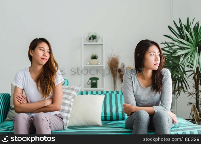 Young Asian lesbian couple argue and turn their back to each other in the period of sad in the bedroom. LGBT couple sulky to another in the bedroom with a sad mood. LGBT lover emotion concept.