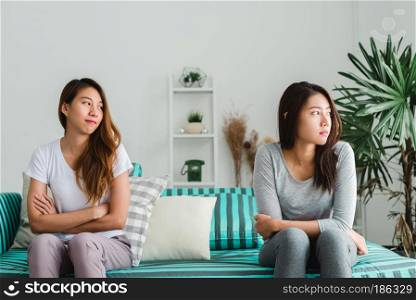 Young Asian lesbian couple argue and turn their back to each other in the period of sad in the bedroom. LGBT couple sulky to another in the bedroom with a sad mood. LGBT lover emotion concept.