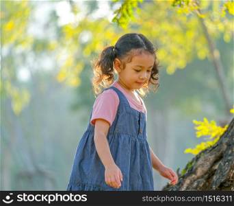 Young Asian little girl play alone in the garden with morning light.