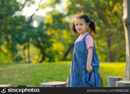 Young Asian little girl play alone in the garden with morning light.