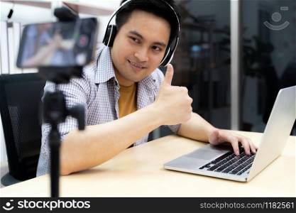 Young asian male gamer casting and broadcasting his online playing video game using smart mobile phone to recording live vlog video. Online influcencer and vlog on social media concept.