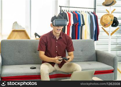 Young asian male gamer casting and broadcasting his online playing video game with VR glasses to recording live vlog video. Online influcencer and vlog on social media concept.