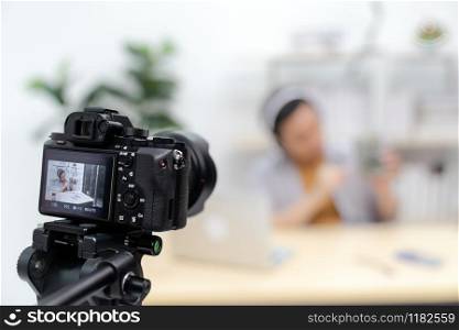 Young asian male IT vlogger and blogger live about Technology upgrand on laptop harddisk using digital camera to recording live vlog video. Online influcencer on social media concept. Focus on camera.
