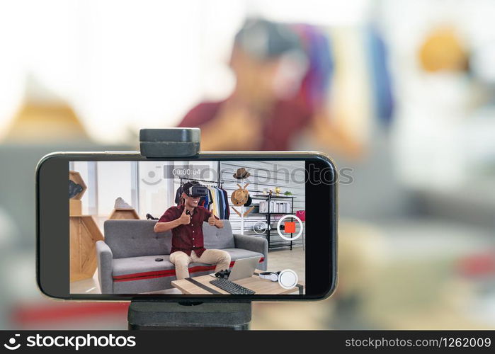 Young asian male online blogger recording live vlog video for review joystick for gaming IT product goods. Online influcencer on social media concept. Focus on mobile phone