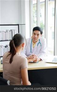 Young Asian male psychiatrist is specialist in psychiatry is talking and encouraging with laptop to Caucasain female Patient in Clinical treatment for emotional symptoms.