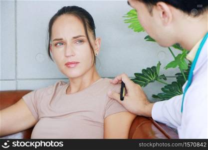 Young asian male psychiatrist is specialist in psychiatry is touching shoulder on Caucasian female Patient and encouraging to her in Clinical treatment for emotional symptoms.
