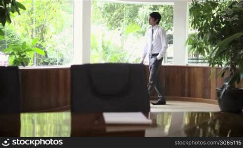 Young Asian man at work as businessman and looking out of the office windows