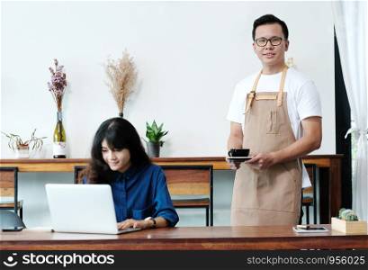 Young asian man barista serving a coffee cup in cafe background, small business owner, food and drink industry