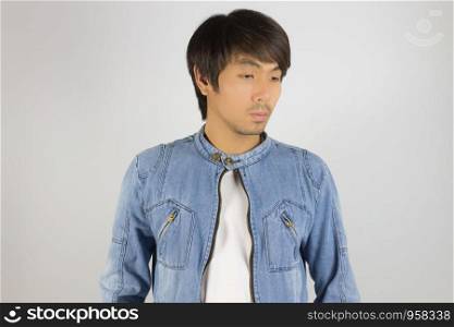 Young Asian Man in Jeans Jacket or Denim Jacket Looking Below at Center Frame. Denim or Jeans Jacket Men Fashion on Gray Background