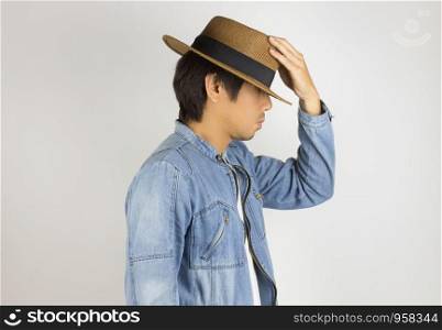 Young Asian Man in Jeans Jacket or Denim Jacket Touch Hat on Side View Pose. Denim or Jeans Jacket Men Fashion on Gray Background