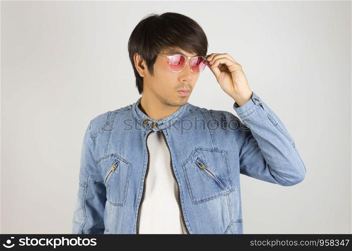 Young Asian Man in Jeans Jacket or Denim Jacket Touching Red Glasses. Denim or Jeans Jacket Men Fashion on Gray Background