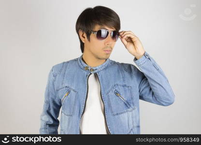 Young Asian Man in Jeans Jacket or Denim Jacket Touching Sunglasses. Denim or Jeans Jacket Men Fashion on Gray Background