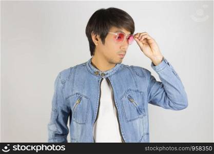 Young Asian Man in Jeans Jacket or Denim Jacket Wear and Touch Red Glasses. Denim or Jeans Jacket Men Fashion on Gray Background