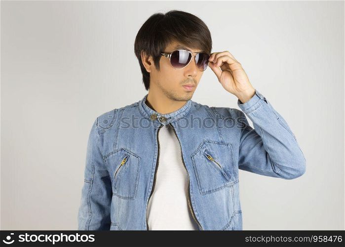 Young Asian Man in Jeans Jacket or Denim Jacket Wear and Touch Sunglasses. Denim or Jeans Jacket Men Fashion on Gray Background