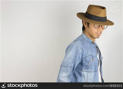 Young Asian Man in Jeans Jacket or Denim Jacket Wear Eyeglasses and Hat on Right Frame. Denim or Jeans Jacket Men Fashion on Gray Background