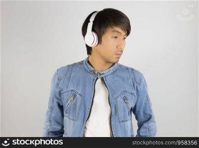 Young Asian Man in Jeans Jacket or Denim Jacket Wear Headphone and Looking Right Frame. Denim or Jeans Jacket Men Fashion on Gray Background