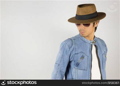 Young Asian Man in Jeans Jacket or Denim Jacket Wear Sunglasses and Hat at Right Frame. Denim or Jeans Jacket Men Fashion on Gray Background