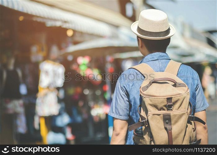 Young asian man traveler traveling backpacker walking in a famous street market in among the many people in asia. filler Vintage Tone and Selective Soft Focus.