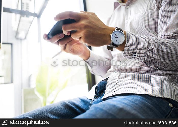 young asian man using mobile device smart phone at a workplace - technology concept