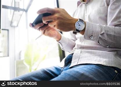 young asian man using mobile device smart phone at a workplace - technology concept