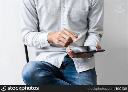 young asian man using pad tablet mobile device at a workplace - technology concept