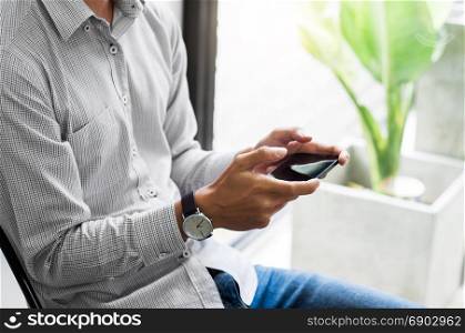 young asian man watching mobile smart phone - device technology and gadget concept