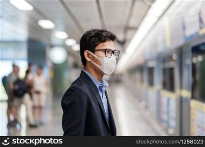 young Asian man wearing protection mask against Novel coronavirus or Corona Virus Disease (Covid-19) at public train station,is a contagious virus that causes respiratory infection.Healthcare concept
