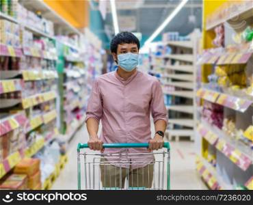 young asian man with shopping cart in supermarket department store and her wearing medical mask for prevention coronavirus(covid-19) pandemic. new normal concept