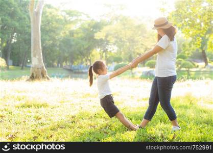 Young asian mother and little daughter playing the park with fun and happiness, family enjoy and relax and leisure together, mom and children smiling laughing in summer day.