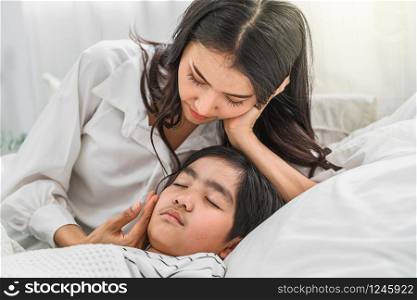 Young Asian mother taking care and checking son Illness on the bed in bedroom house, mom worried high temperature and virus flu, children health care and Contagious disease of corona influenza concept
