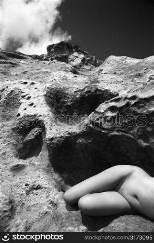 Young Asian nude woman lying on side on rock.