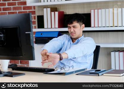 Young asian office man stretching body for relaxing while working with computer at his desk, office lifestyle, business situation