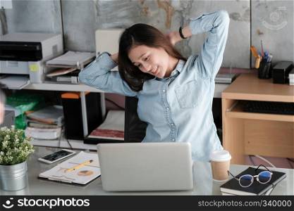 Young asian office woman stretching body for relaxing while working with laptop computer at her desk, office lifestyle, business situation