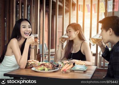 Young asian people having fun at drinking with cheering with beer at restaurant.