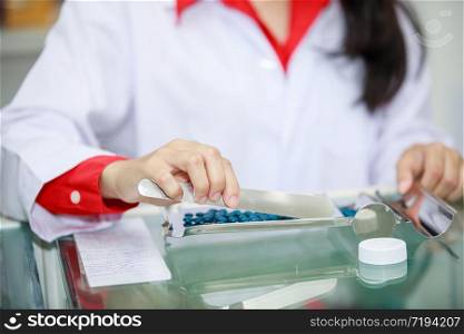 young asian pharmacist counting and packages medicine in pharmacy store Thailand