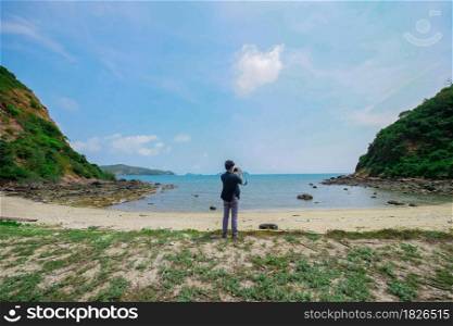 Young Asian photographer taking picture with camera on the beach