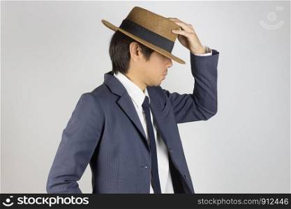 Young Asian Portrait Businessman in Navy Blue Suit Touch Hat at Side View on Grey Background