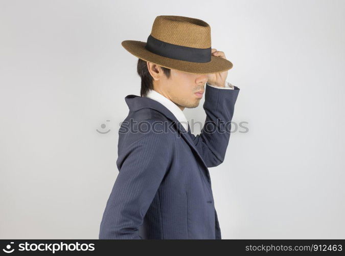 Young Asian Portrait Businessman in Navy Blue Suit Touch Hat Brim at Side View on Grey Background