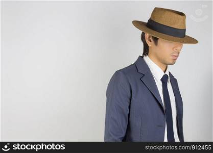 Young Asian Portrait Businessman in Navy Blue Suit Wear Hat at Right Frame on Grey Background