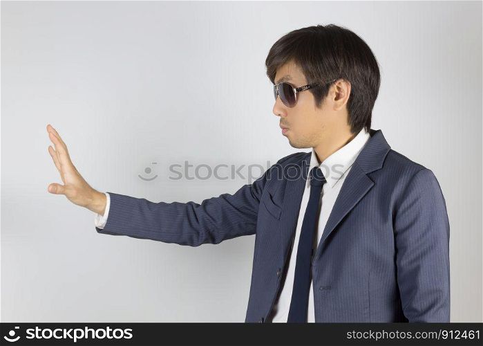 Young Asian Portrait Businessman in Navy Blue Suit with Stop Hand Pose on Grey Background