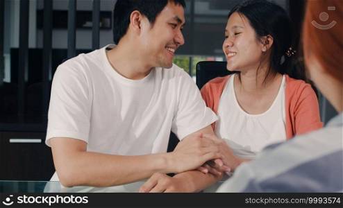 Young Asian Pregnant couple sign contract documents at home, Japanese family consulting with real estate financial advisor, Buying new house and handshaking with broker in living room in the morning.
