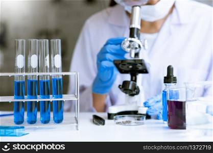 Young Asian scientist Working looking through a microscope doing research for analyzing a Experiments sample in a forensic laboratory