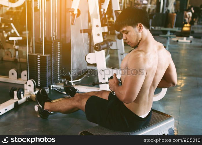 Young asian sportsman pull still weight for building muscle at indoor gym.