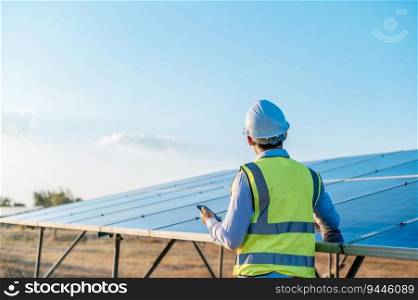 Young Asian technician man standing and talking on smartphone between long rows of photovoltaic solar panels, copy space