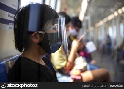 Young asian wearing surgical face mask protective for spreading of disease virus COVID-19 or Coronavirus outbreak prevention sitting in subway at public area