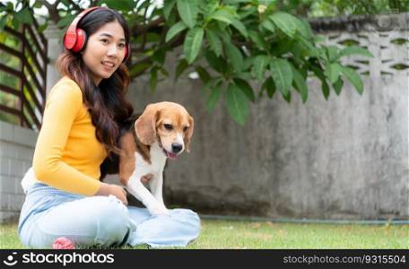 Young asian woman and beagle puppy relaxing on weekends in the front yard.