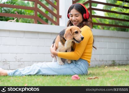 Young asian woman and beagle puppy relaxing on weekends in the front yard.