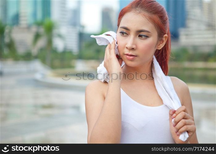 Young asian woman athlete wiping her towel in park city